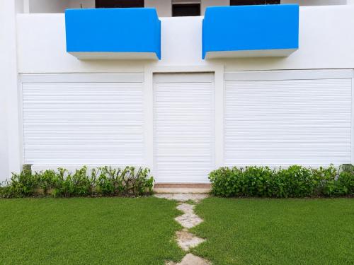 a white garage door with two blue boxes on it at Plage al amin eden in Fnidek