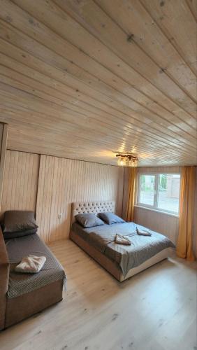 a bedroom with two beds in a room with wooden ceilings at Happy Time in Sredneye Vodyanoye