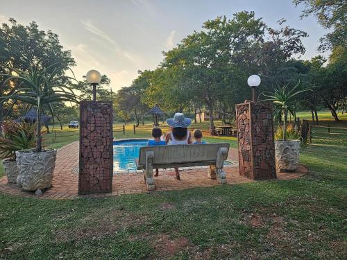 a group of people sitting on a bench near a pool at Buyskop Lodge, Conference & Spa in Bela-Bela