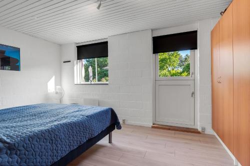 a bedroom with a blue bed and two windows at Feriehus 1149 in Ringkøbing