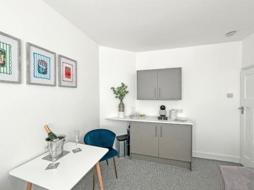 a white kitchen with a white table and blue chairs at Vine - Uk51860 in Ely