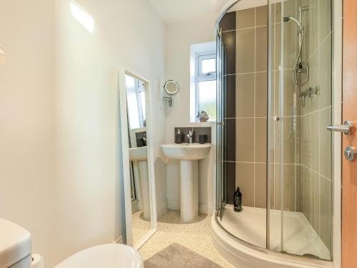 a bathroom with a shower and a toilet and a sink at Marram Dune Beach House in Brean