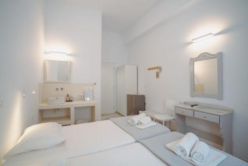 a white bathroom with two beds and a sink at Hotel Mantalena in Antiparos