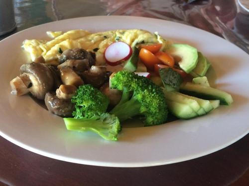 un piatto di cibo con broccoli, funghi e verdure di Nxabii Cottages a Kasane