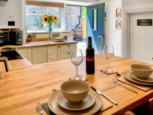 a table with a bottle of wine and two glasses at The Old Posthouse Barn - Uk50191 in Weare