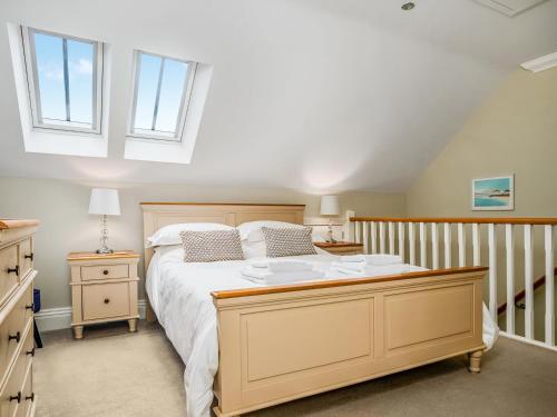 a bedroom with a large bed and two windows at Ridings Cottage in Helmsley