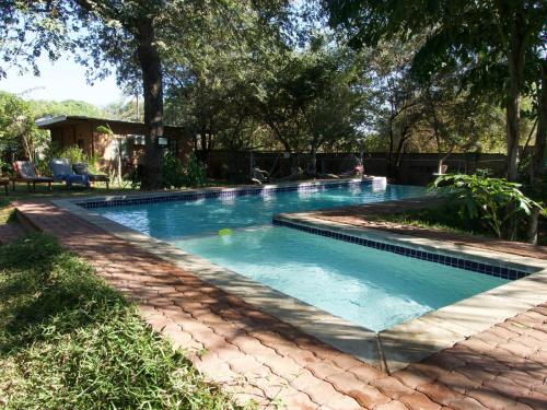 una piscina in un giardino con alberi di Nxabii Cottages a Kasane