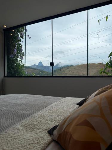a bedroom with a large window looking out at a mountain at Mirante de itaipava in Itaipava