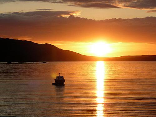 a boat in the water at sunset at The Narrows in Poolewe