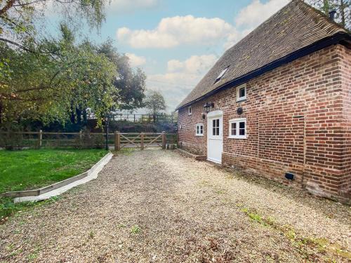 a brick building with a white door and a fence at The Granary in Little Chart