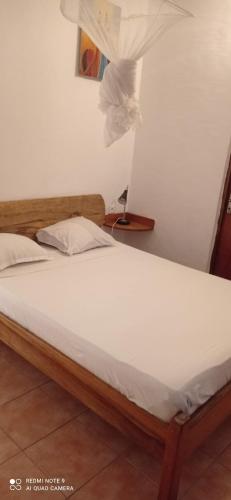 ein Bett in einem Zimmer mit einem weißen Bettlaken in der Unterkunft Laduno in M'bour