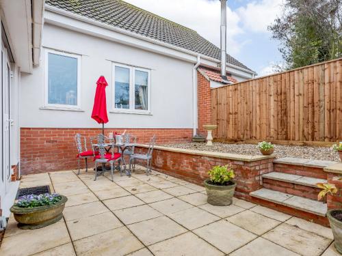 a patio with a table and a red umbrella at Vineyard's Apartment - Uk36748 in Ely