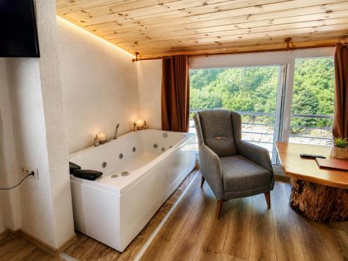 a bathroom with a tub and a chair and a desk at Ayder River Suite by Karadeniz in Ardeşen