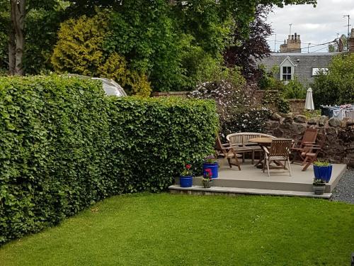 a garden with chairs and a table and a hedge at Cloud Cottage in Duns