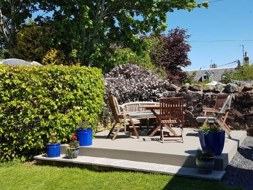 a patio with chairs and a table in a garden at Cloud Cottage in Duns