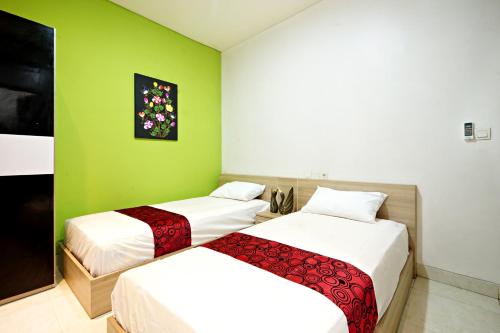 two beds in a room with green walls at D'Pande Kuta in Kuta