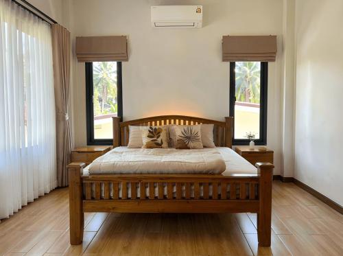 a bedroom with a wooden bed with two windows at Thara Bohemia Villa in Hinkong