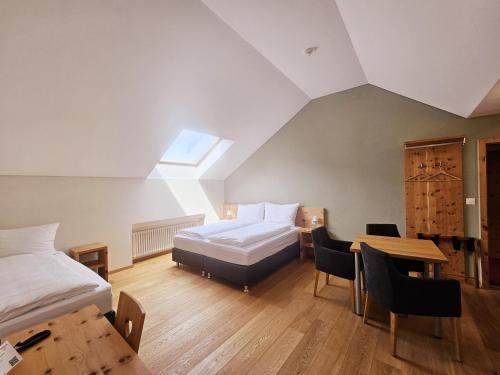 a bedroom with two beds and a desk and a table at Hotel Alpenstadt in Chur