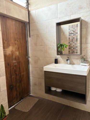 a bathroom with a sink and a mirror and a shower at Cabañas Casa Tucano in San Ramón
