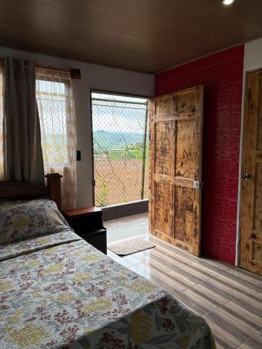 a bedroom with a bed and a large window at Cabañas Casa Tucano in San Ramón