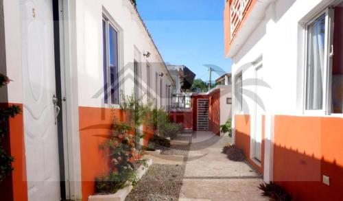 an alley between two buildings with orange and white at Hogar flores in La Ceiba
