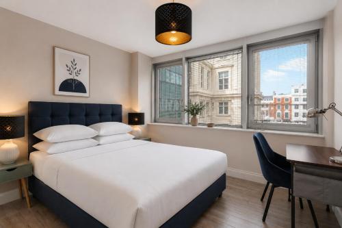 a bedroom with a bed and a desk and windows at Airhost's Brighton's Best Green Diamond Escape with Sea Views in Brighton & Hove