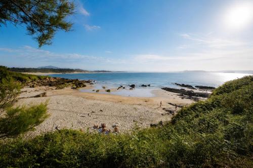 a beach with people on the sand and the water at Kampaoh Somo Playa in Somo