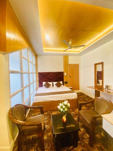 a hotel room with a bed and a table and chairs at Rahat Resort in Srinagar