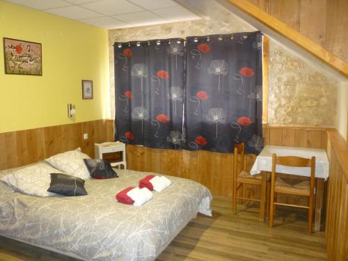 a bedroom with a bed and a window with red flowers at La SERPAUDERIE in Saint-André-de-Lidon