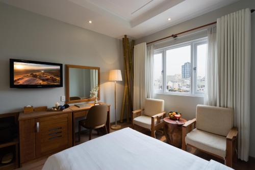 a hotel room with a bed and a desk and a window at Silverland Yen Hotel in Ho Chi Minh City