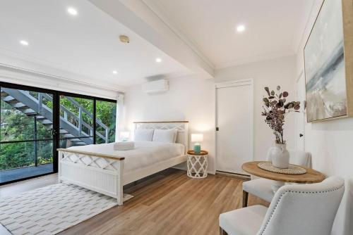 a white bedroom with a bed and a table and chairs at North Avoca Coastal Escape in North Avoca