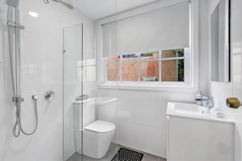 a white bathroom with a toilet and a sink at North Avoca Coastal Escape in North Avoca