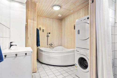 a bathroom with a tub and a washing machine at SJ232-Hejls-Humlevaenget-8 in Hejls