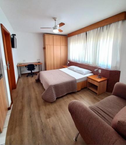 a bedroom with a bed and a desk and a couch at JK Studio centro, você merece o melhor! in Novo Hamburgo