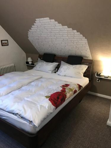 a large bed with white sheets and red flowers on it at Pension und Restaurant La Casa in Undeloh