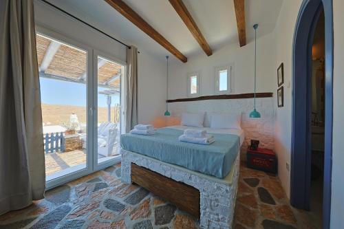 a bedroom with a bed and a large window at EMERALD Villa in Kithnos