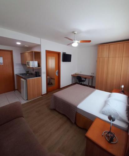 a bedroom with a bed and a couch and a kitchen at JK Studio centro, você merece o melhor! in Novo Hamburgo