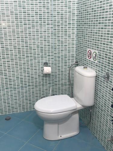 a bathroom with a toilet and a tiled wall at Serenade Beach in Durrës
