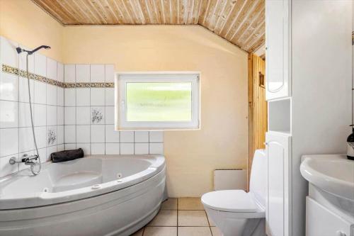 a bathroom with a tub and a toilet and a window at SJ296-Hejls-Ae-Skovbryn-37 in Hejls