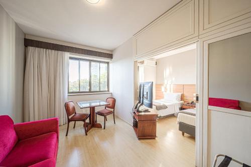 a living room with a couch and a tv and a bed at Hotel Prinz in Joinville