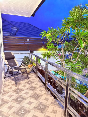 a balcony with a chair and palm trees at Swansea Villa 3 BR in Ban Huai Yai