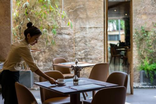 a woman standing in front of a table with a cup at Silverland Yen Hotel in Ho Chi Minh City
