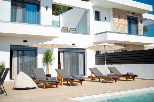 a building with chairs and umbrellas next to a swimming pool at Villas Pasha in Faliraki