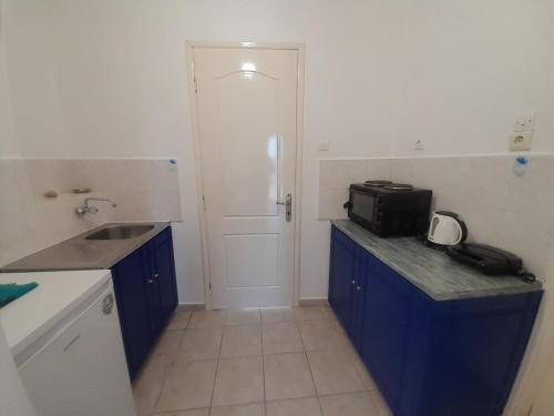 a kitchen with blue cabinets and a sink and a door at Studios RENA in Fournoi