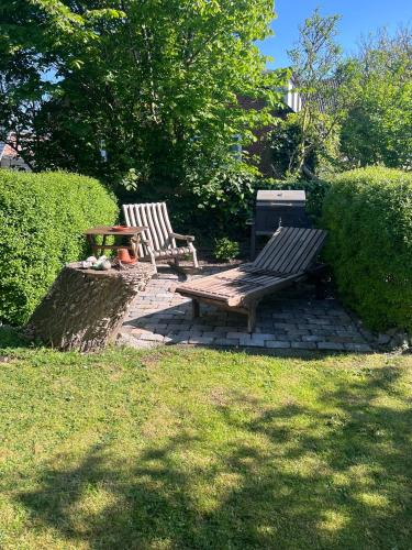 two wooden benches and a picnic table in a yard at HaRE Ferienwohnungen een in Langeneß