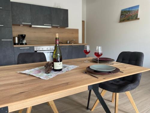 a wooden table with a bottle of wine and two glasses at Apartment Bienenfresser in Vogtsburg