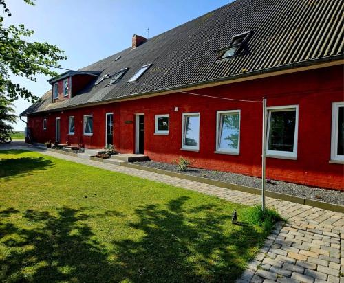 a red house with a black roof and a yard at HaRE Ferienwohnungen Käptn Magda in Langeneß