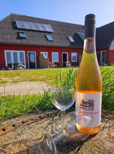 a bottle of wine sitting next to a glass at HaRE Ferienwohnungen Käptn Magda in Langeneß