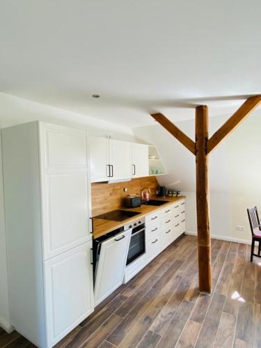 a kitchen with white cabinets and a wooden floor at HaRE Ferienwohnungen VEER in Langeneß