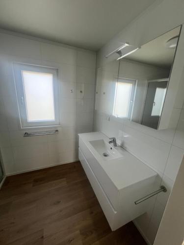 a white bathroom with a sink and a mirror at Green Flower in Renesse